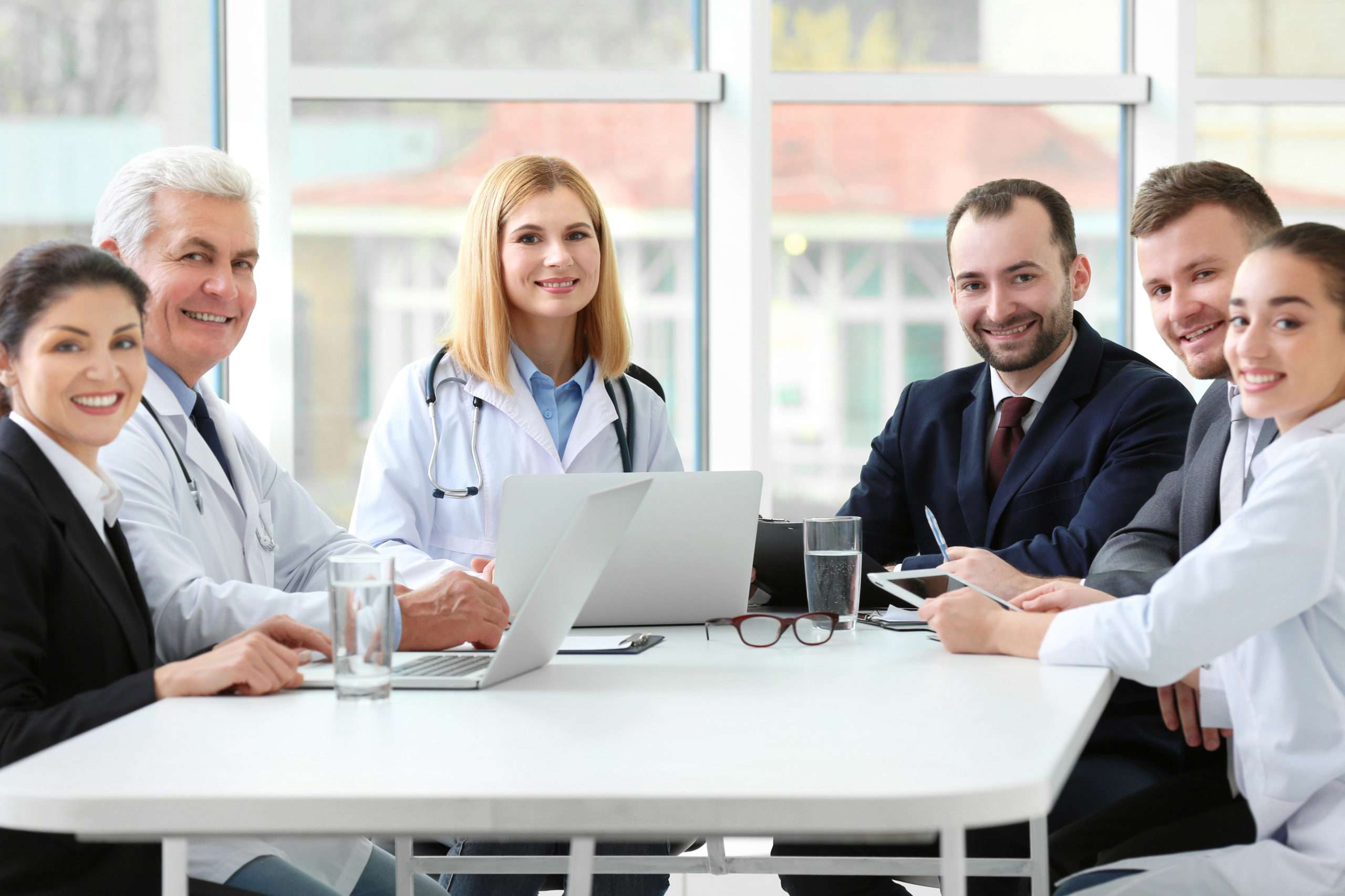 A diverse team of clinicians and colleagues smiling around a conference table